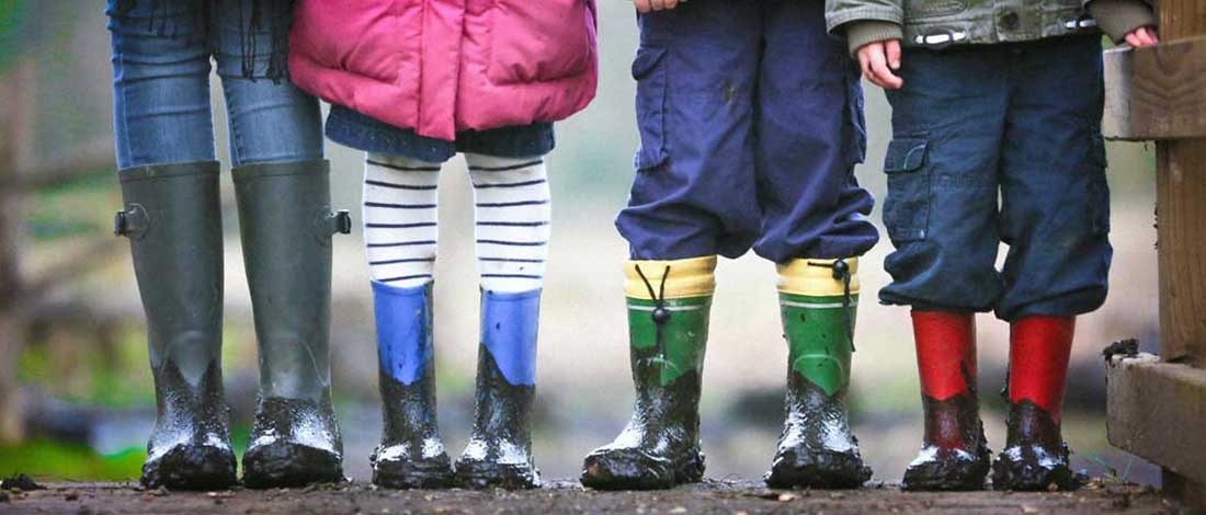 Imagen de la parte inferior (los pies con botas de barro) de 4 niños